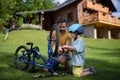 Father with little son together preparing bicycle for a ride, pumping up tyres in garden in front of house.