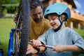 Father with little son together preparing bicycle for a ride, pumping up tyres in garden in front of house.