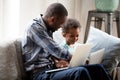 Father with little son using computers sitting on couch