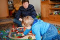 Father and little toddler boy playing with wooden railway, indoors. Happy family, man and cute child moving trains. Royalty Free Stock Photo