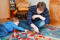 Father and little toddler boy playing with wooden railway, indoors. Happy family, man and cute child moving trains. Royalty Free Stock Photo