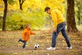 Dad and son having fun outdoors: little boy playing soccer with father in autumn park Royalty Free Stock Photo