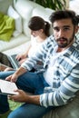 Father looking at camera while daughter using laptop in the living room Royalty Free Stock Photo