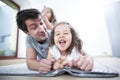 Father looking at cheerful daughter lying on blanket at home