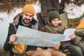 Father looking at map and son looking at tablet sitting