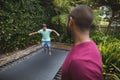 Father looking at son jumping on trampoline Royalty Free Stock Photo