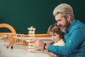 Father looking at son playing jenga game. Cute pupil and his father in classroom. Supporting pupils at school Royalty Free Stock Photo