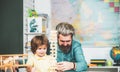 Father looking at son playing jenga game. Little boy pupil with happy face expression near desk with school supplies Royalty Free Stock Photo