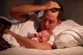 Father Lying In Bed With Crying Baby Daughter