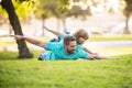 Father lying on grass, with excited happy little child son on shoulder. Carefree two man generations family having fun Royalty Free Stock Photo