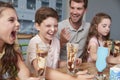 Father Making Ice Cream Sundaes With Children At Home