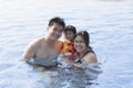 father mather and dauther happiness time in swimming pool smiling to camera