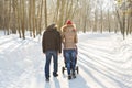 Father and mother with baby carriage in winter forest Royalty Free Stock Photo