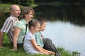 Father, mother, boy and girl is sitting near pond Royalty Free Stock Photo