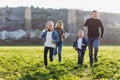 Father, mother and children run through a green field. Royalty Free Stock Photo