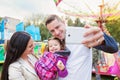 Father, mother and daughter in amusement park taking selfie Royalty Free Stock Photo