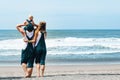 Father, mother, funny baby son walk by beach along sea