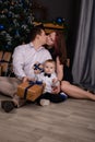 father and mother holds their little blonde son and pose near the Christmas tree. Concept of family holiday. Young Royalty Free Stock Photo