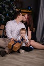 father and mother holds their little blonde son and pose near the Christmas tree. Concept of family holiday. Young Royalty Free Stock Photo