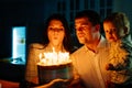 a father and mother with a kid son make a wish and blow out candles on the cake. Royalty Free Stock Photo