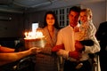 a father and mother with a kid son make a wish and blow out candles on the cake. Royalty Free Stock Photo