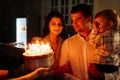 a father and mother with a kid son make a wish and blow out candles on the cake. Royalty Free Stock Photo