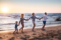father, mother, little son and adult daughter, having fun holding hands, playing on beach during summer holidays Royalty Free Stock Photo