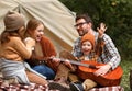 Father, mother and little son sitting near tourist tent and playing guitar during camping Royalty Free Stock Photo