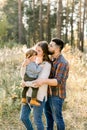 Father, mother and little son are walking in the autumn pine forest at sunset. Happy family enjoying their time, hugging Royalty Free Stock Photo