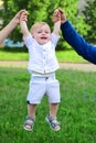 Father and mother parents holding child baby hands. Cute little baby on the meadow field. Toddler child walking outdoor Royalty Free Stock Photo