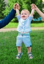 Father and mother parents holding child baby hands. Cute little baby on the meadow field. Toddler child walking outdoor Royalty Free Stock Photo