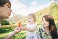 Father and mother play with his daughter with soapbubble