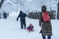 Father and mother pulling children in sleds during snowstorm