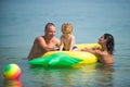 Father and mother with son play ball in water. mother and father with small baby boy in sea water.