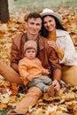 Father and mother with son sitting in the autumn Park. Portrait of a Golden autumn Family in a nature Park. Royalty Free Stock Photo