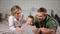 Father mother and son watch instructional video lying on bed