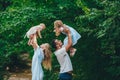 Father and mother throwing his children in the air in summer park Royalty Free Stock Photo