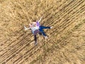 Father, mother and toddler daughter lying back on dry wheat field, top view from drone, quadcopter remote control is in men hand Royalty Free Stock Photo