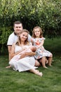 Father, mother and two children, baby girl and little daughter on the grass on summer day. Happy family sitting together outdoors Royalty Free Stock Photo