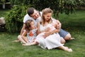 Father, mother and two children, baby girl and little daughter on the grass on summer day. Happy family sitting together outdoors Royalty Free Stock Photo