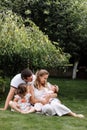 Father, mother and two children, baby girl and little daughter on the grass on summer day. Happy family sitting together outdoors Royalty Free Stock Photo