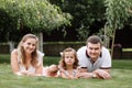 Father, mother and two children, baby girl and little daughter on the grass on summer day. Happy family sitting together outdoors Royalty Free Stock Photo