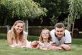 Father, mother and two children, baby girl and little daughter on the grass on summer day. Happy family sitting together outdoors Royalty Free Stock Photo