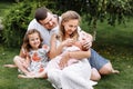 Father, mother and two children, baby girl and little daughter on the grass on summer day. Happy family sitting together outdoors Royalty Free Stock Photo