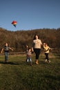 Father and mother walk with daughter and son on green grass at sunset and launch multicolored kite into sky. Have fun spending Royalty Free Stock Photo