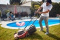 Father Mowing the Lawn as Mother and Children Enjoy Poolside Bliss