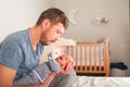 Father and newborn in Scandi bedroom interior. The father sings a lullaby to the child. Parent calms the baby before going to bed