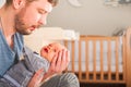 Father and newborn in Scandi bedroom interior. The father sings a lullaby to the child. Parent calms the baby before going to bed