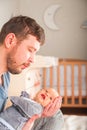 Father and newborn in Scandi bedroom interior. The father sings a lullaby to the child. Parent calms the baby before going to bed