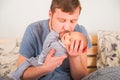 Father and newborn in Scandi bedroom interior. The father sings a lullaby to the child. Parent calms the baby before going to bed